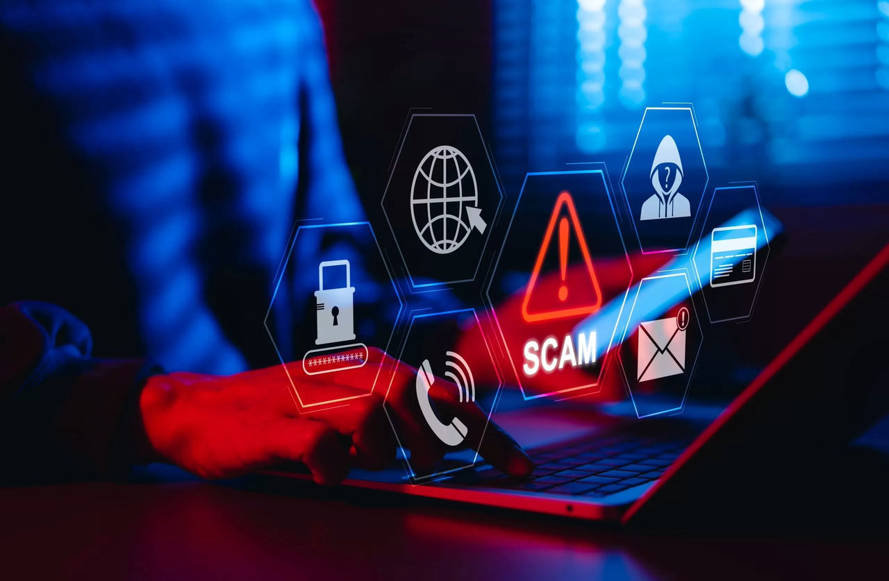 Person typing on laptop with overlay of graphics warning of a scam
