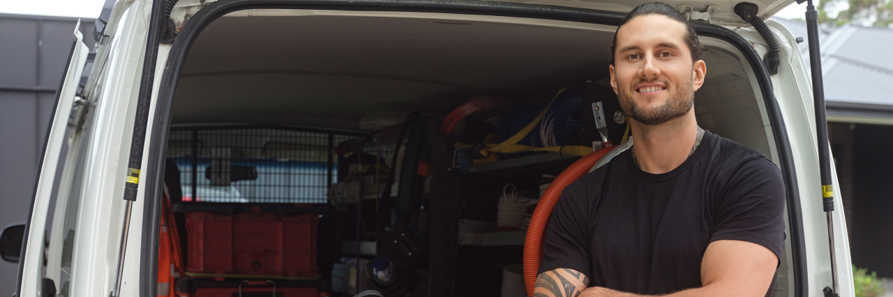 Tradesman standing in front of work van