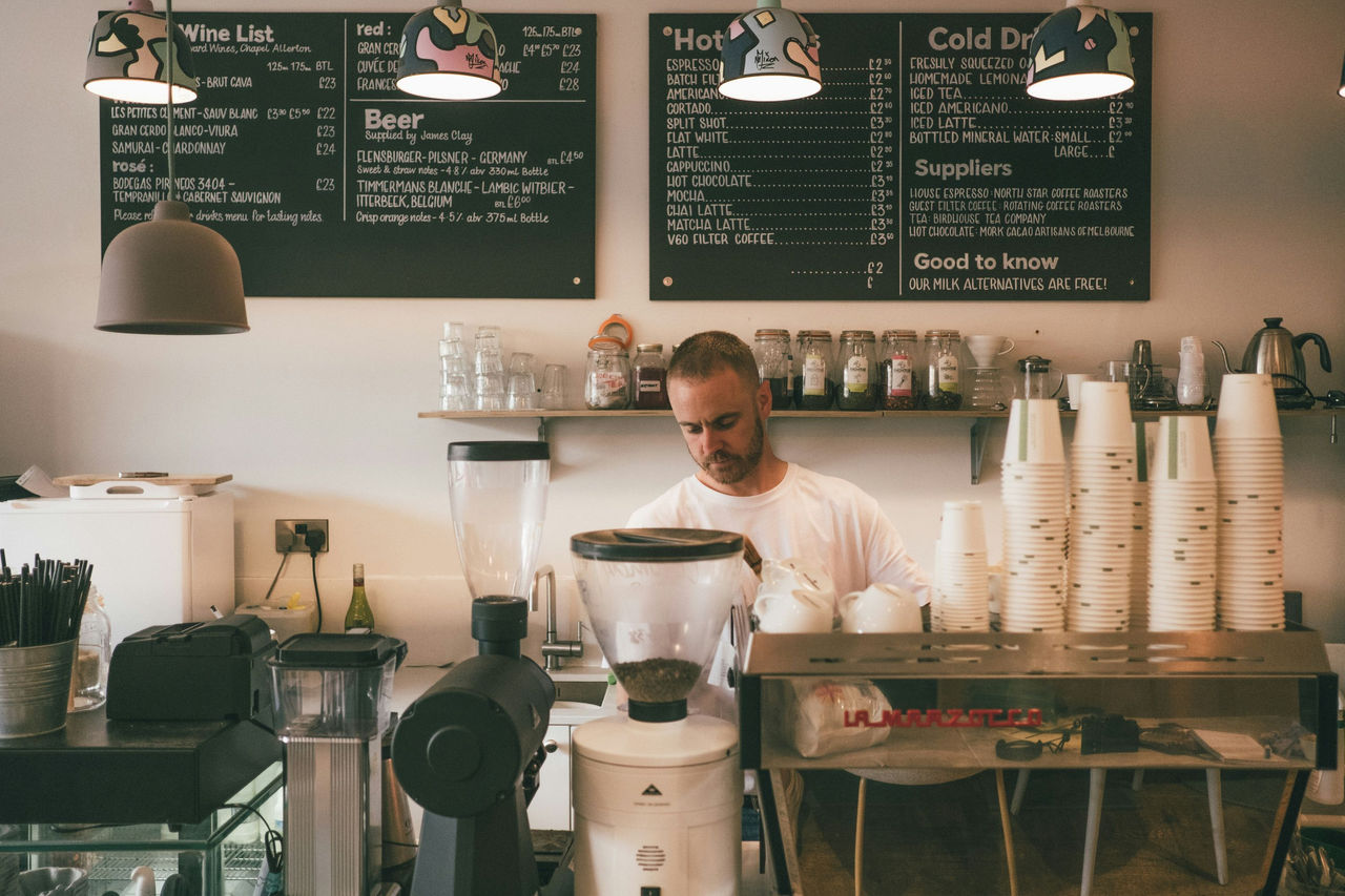 Small business owner standing in front a coffee machine at his cafe