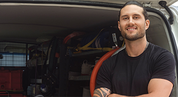 Tradesman standing in front of work van