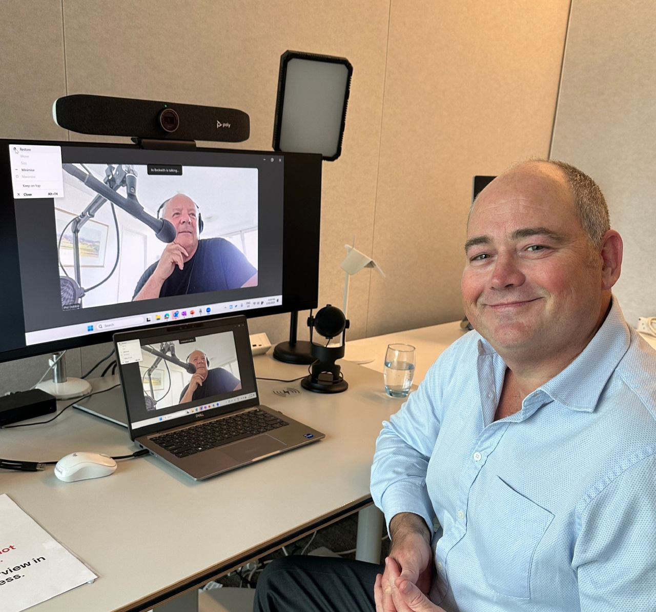 man sitting in front of laptop on video call with man recording podcast