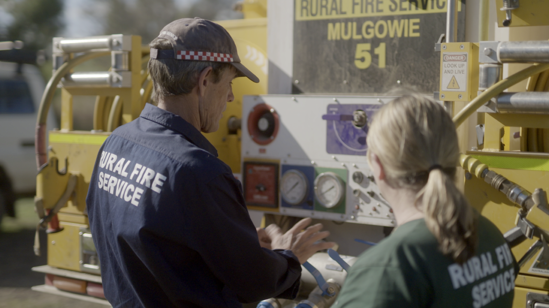 A man and a woman stand in front of a fire truck.