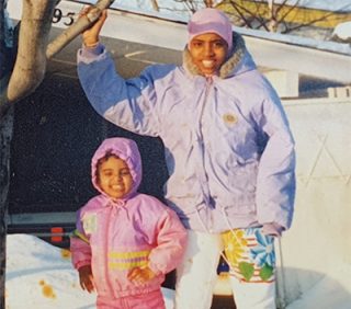 One young child with an older sibling, with jackets on in the snow