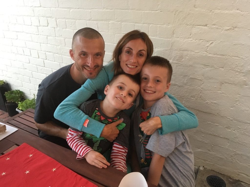 A man and woman with two young boys all sitting together and smiling