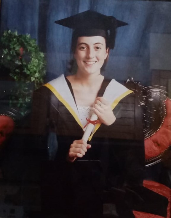 Photo of woman smiling in university graduation gown holding certificate