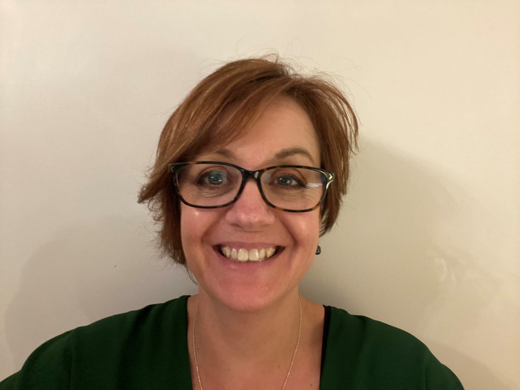 Woman with short brown hair smiling, wearing glasses