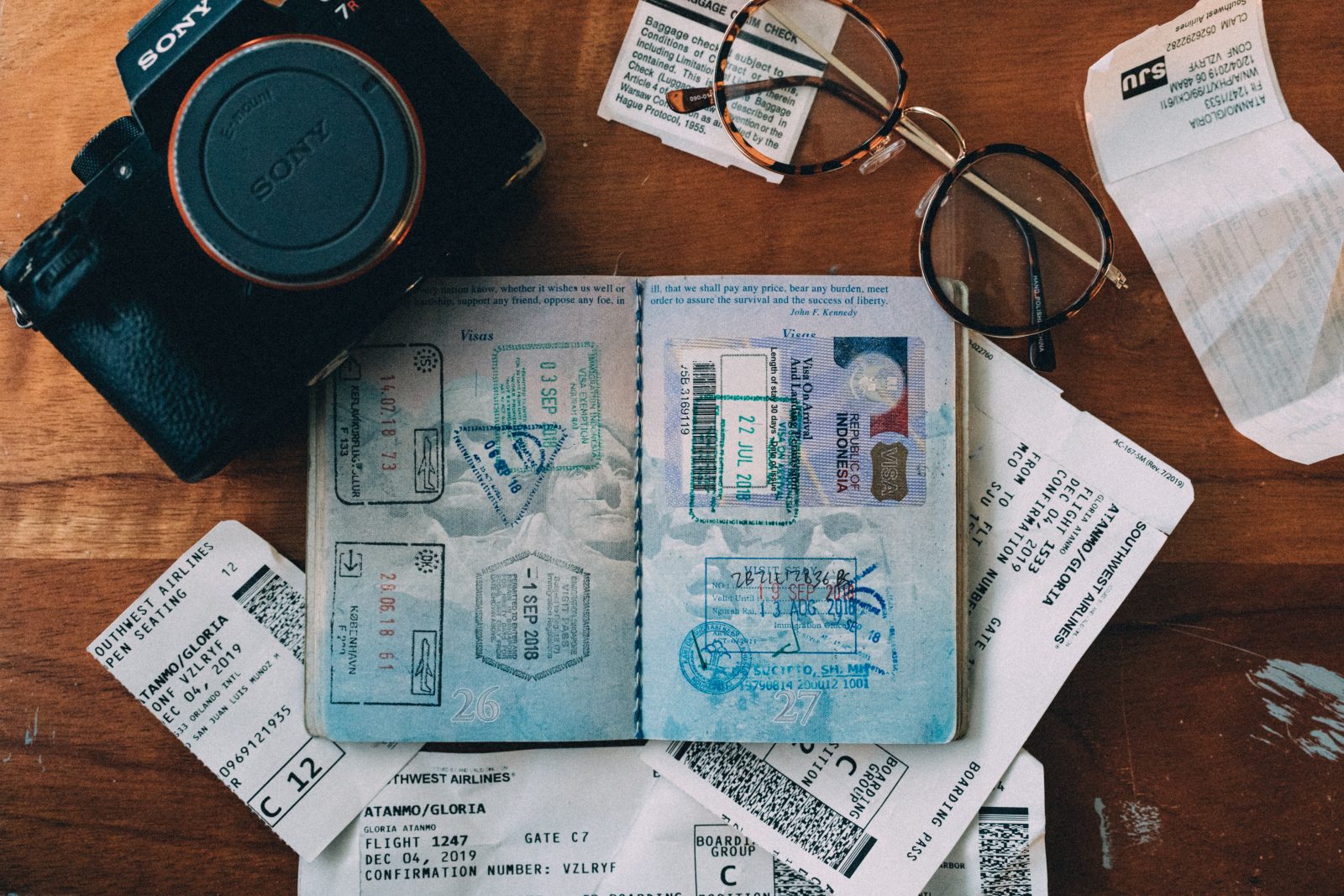 Flat lay image of a passport, plane tickets and a camera.