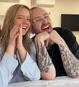 A photo of two people smiling as they sit at a table together.