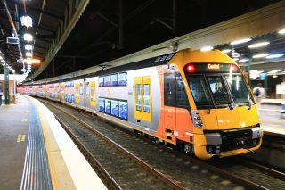 A photo of a train at a station platform at night.