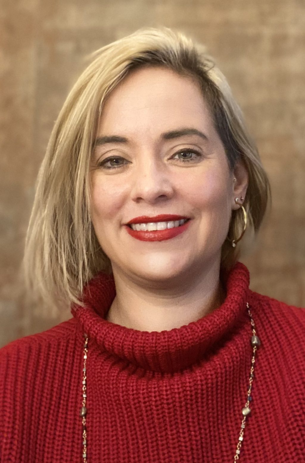 A headshot of a woman smiling looking directly to the camera