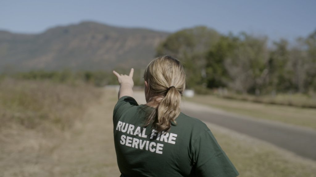 A woman wearing a Rural Fire Service t-shirt surveys the landscape.