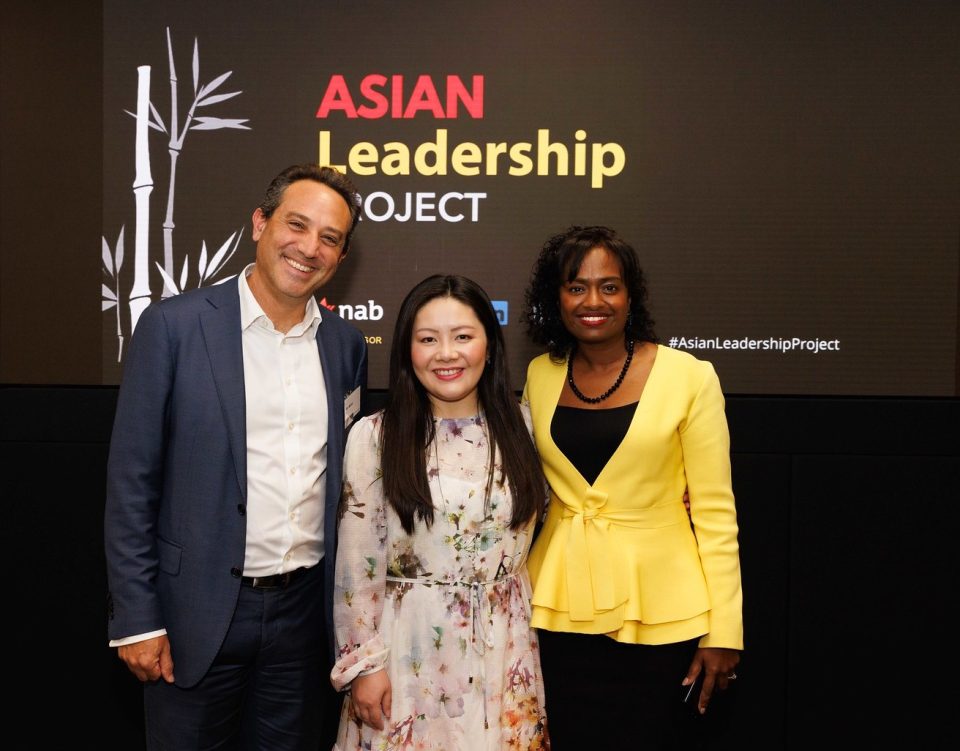 Three people stand together smiling. They are standing in front of a sign for the Asian Leadership Conference.
