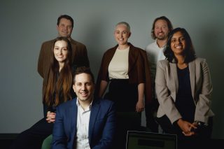 A group of people smile pose for a photo, smiling.