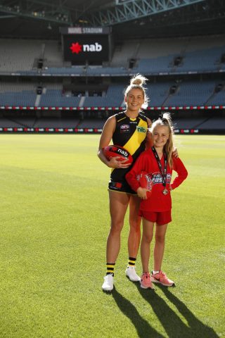 Katie Brennan with a young Auskicker, standing on a footy field