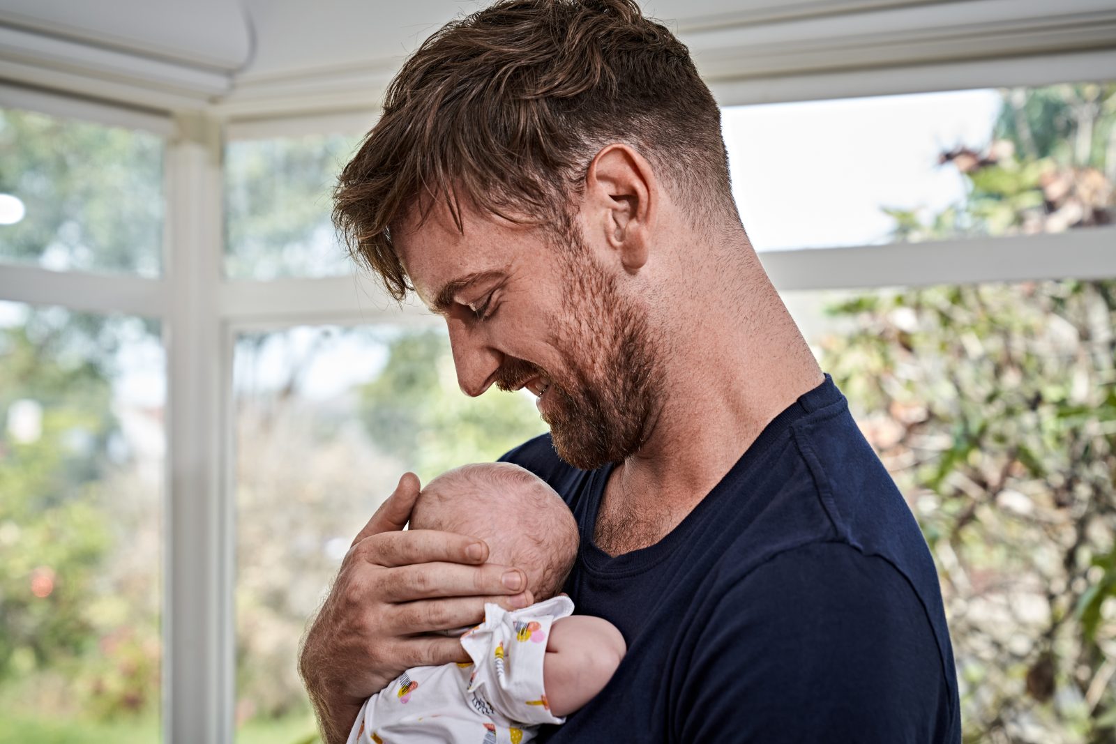 Father holding baby in front of window
