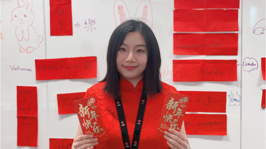 NAB colleague Enqi Xu in traditional red dress holding two red packets