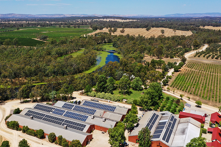 An overhead shot of Tahbilk winery, with green fields and trees in background, and solar panels on buildings in the foreground