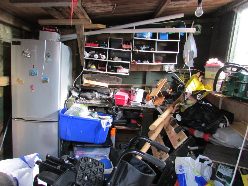 A room filled with various items including a fridge, tools and other miscellaneous goods.
