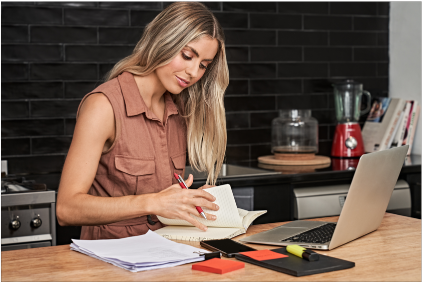 Young woman sitting in front of a laptop and paperwork