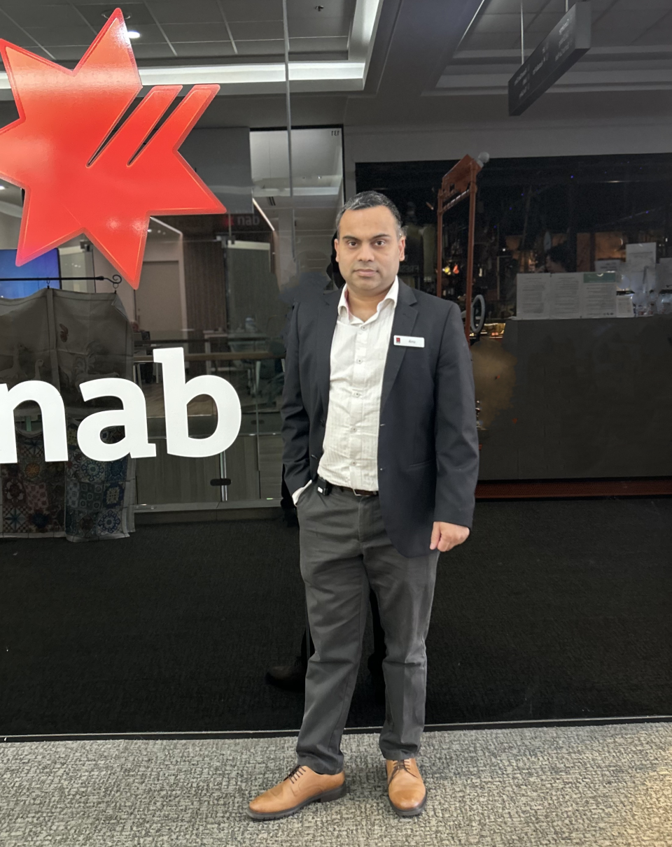 Man in suit standing in front of NAB logo