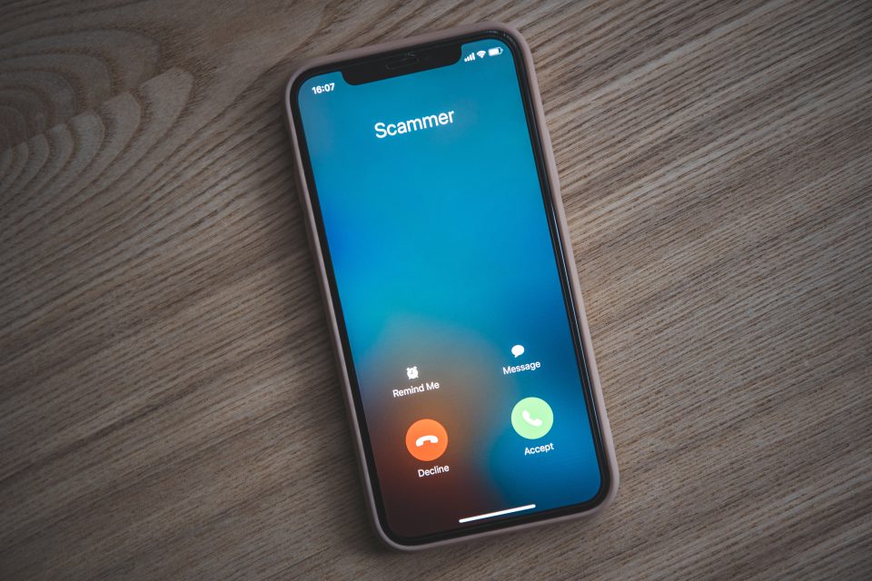 Flat lay image of an iphone with a scammer calling.