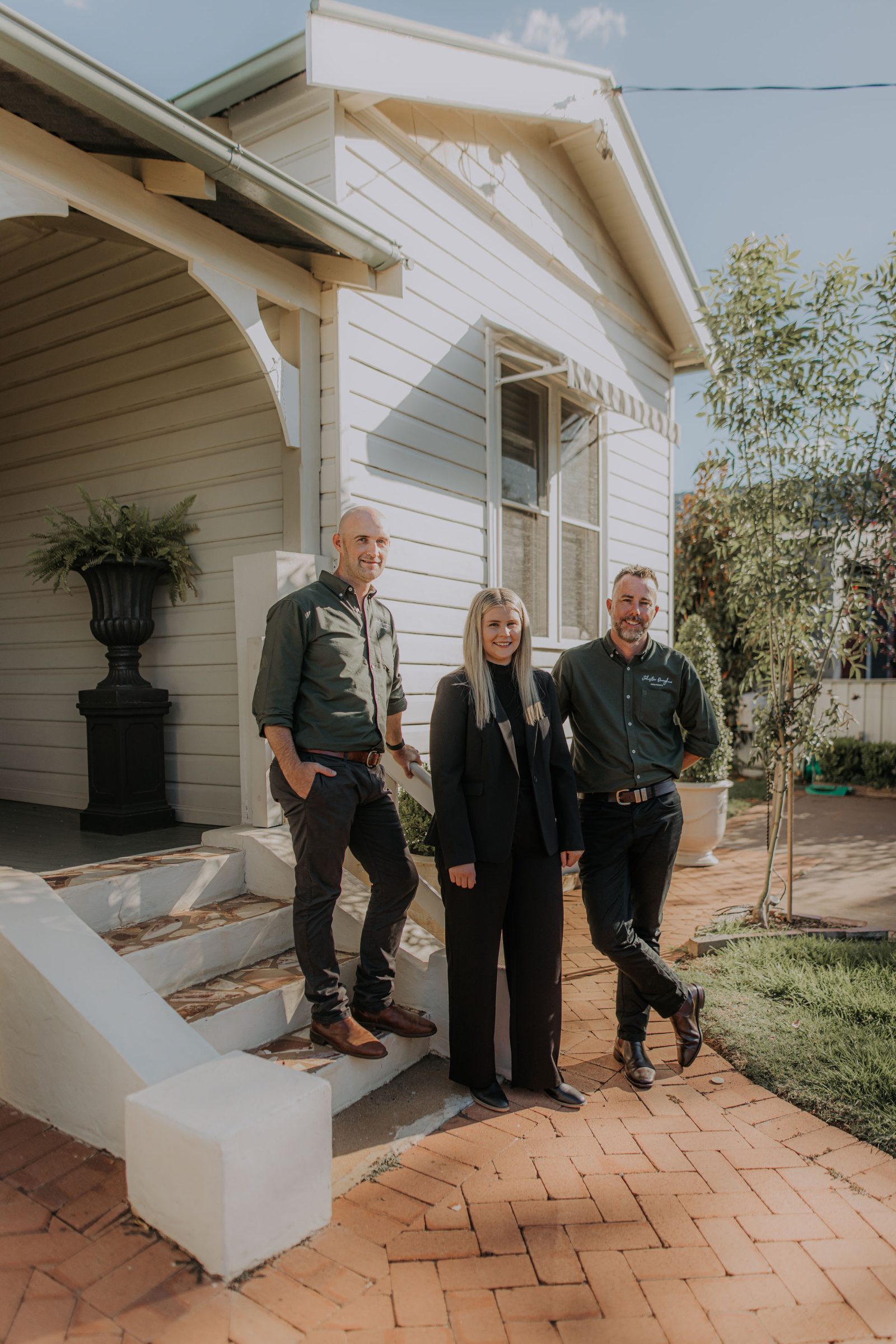 Two men and a woman standing in front of a home