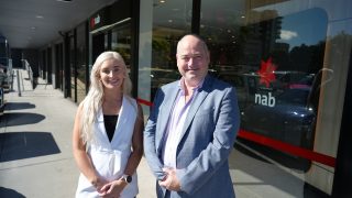 Man and woman standing on street in front of a bank branch