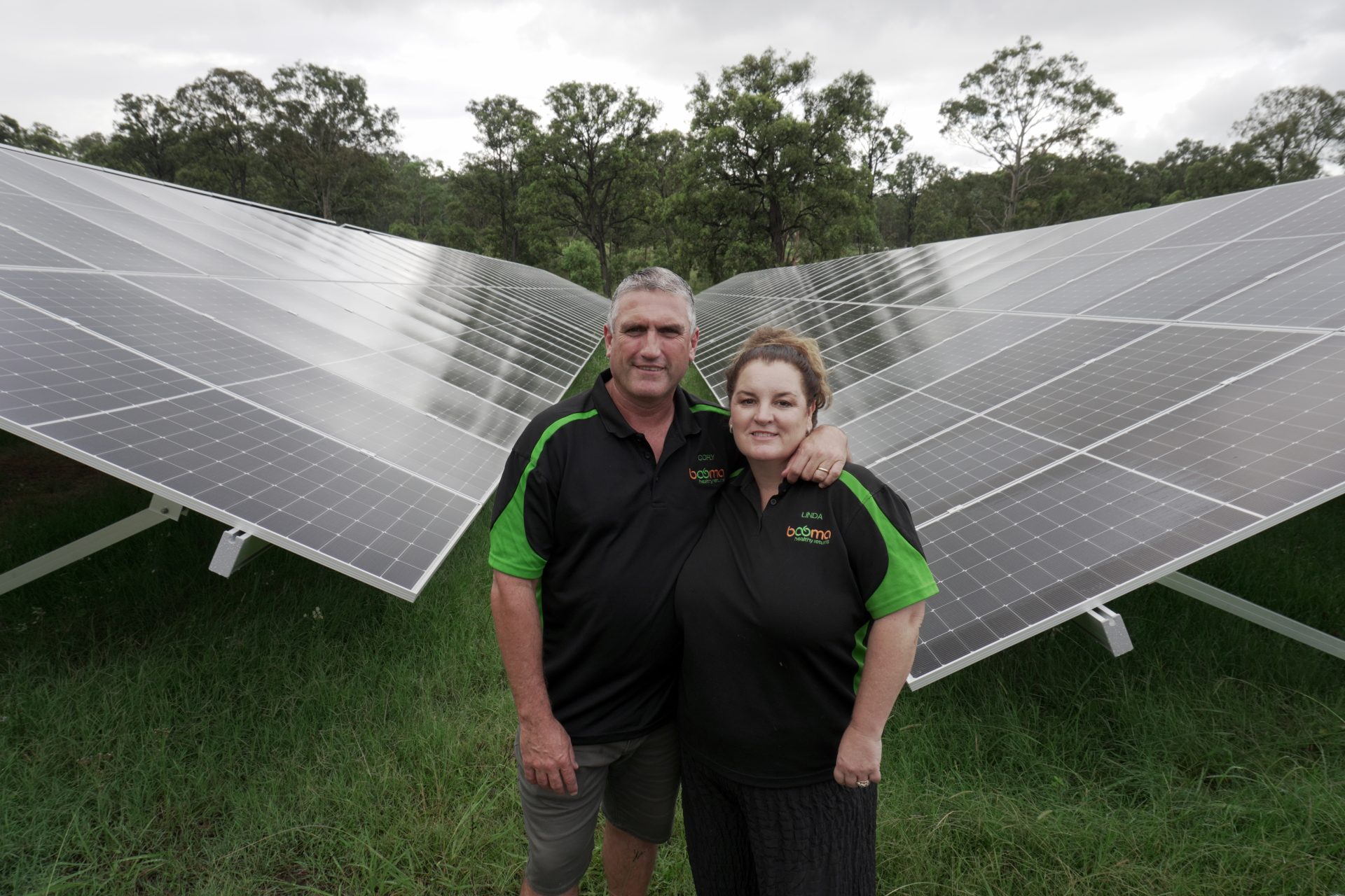 Cory and Linda stand in front of two large solar panels